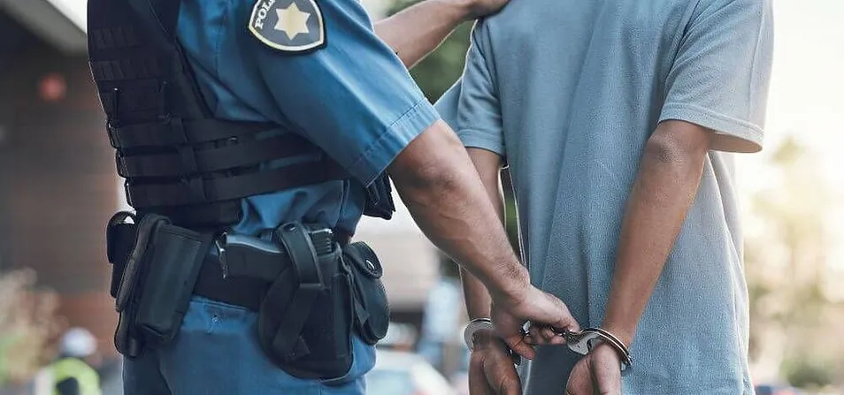 Police officer standing beside a person in handcuffs